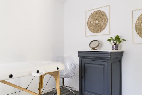 Table de bien-être, chaise transparente et commode gris ardoise surmontée de plantes