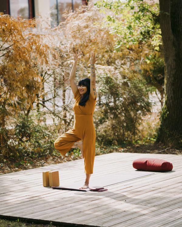 Posture de l'arbre, bras levés, sur une terrasse en bois